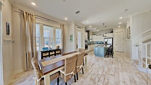 A spacious kitchen with a central island, white cabinetry, and a dining area with wicker chairs. - "Holiday House" 3BR/2.5 Bath at Prominence (Santa Rosa Beach)
