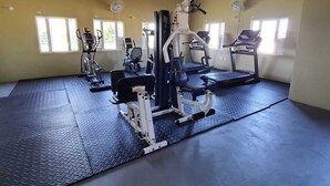 Et fitnesscenter med forskellig træningsudstyr, heriblandt løbebånd, vægtbænk og motionscykler.