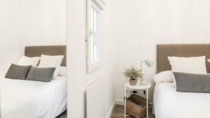 Une chambre à coucher au style minimaliste, avec deux lits, une petite table et une lampe, ainsi qu’un radiateur.