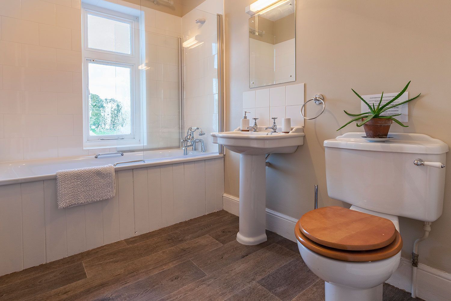A modern bathroom with a bathtub, sink, toilet, and a window.