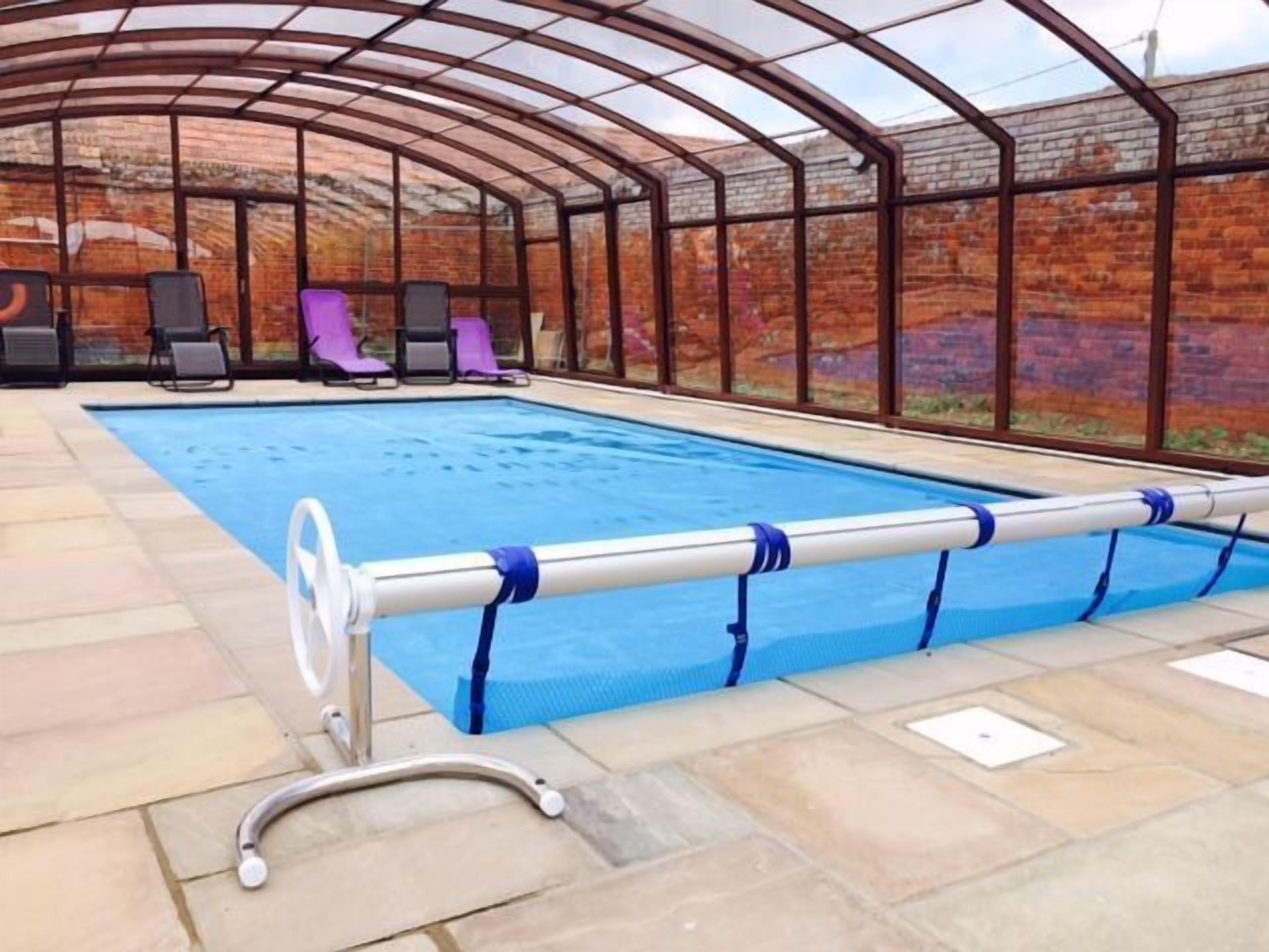 Ein Pool mit Glasumrandung, Liegestühlen und einem Metall-Poolzaun.