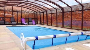 Une piscine dotée d’une enceinte en verre, de chaises longues et d’une barrière métallique.