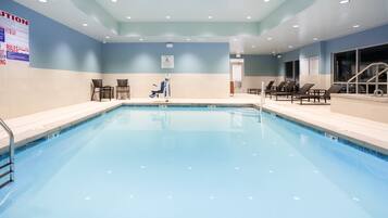 Een binnenzwembad, ligstoelen bij het zwembad