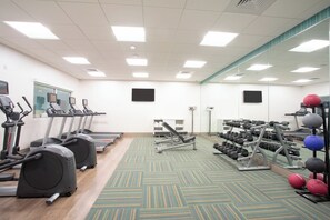 Ein Fitnessstudio mit Laufbändern, Crosstrainern und Gewichten.