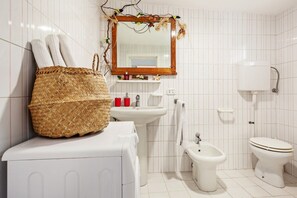 A bathroom with a white sink, bidet, toilet, and a large woven basket on the counter. - GuestHost - NEW!Palazzo dei Diamanti! Pets Friendly (Ferrara)