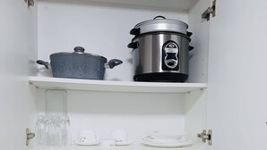 A kitchen with a sink, a stove, a pot, and a slow cooker on the shelves. - Modern - Studio Unit Near NAIA3 (Pasay)