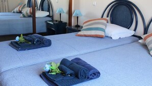 Une chambre d’hôtel avec deux lits, chacun recouvert d’une courtepointe à rayures bleues, agrémentée d’oreillers et de serviettes soigneusement pliées.