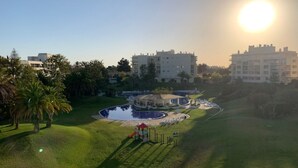 Un parc avec une piscine, une aire de jeux et des bâtiments en arrière-plan.