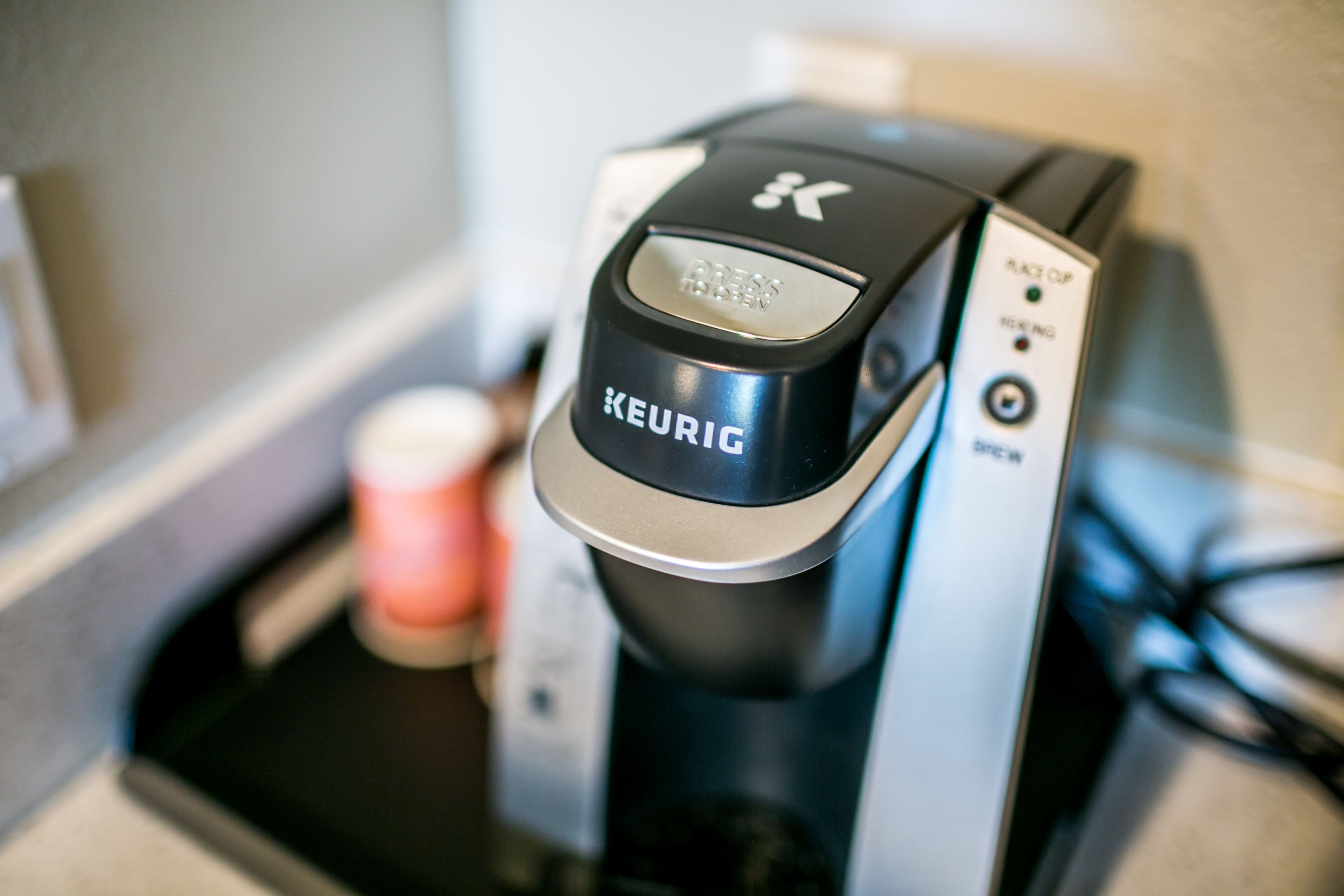 Une machine à café Keurig dotée d’un bouton portant l’inscription « PRESS » et d’un panneau de commande avec un bouton « PUSH » et un indicateur « POWER ».