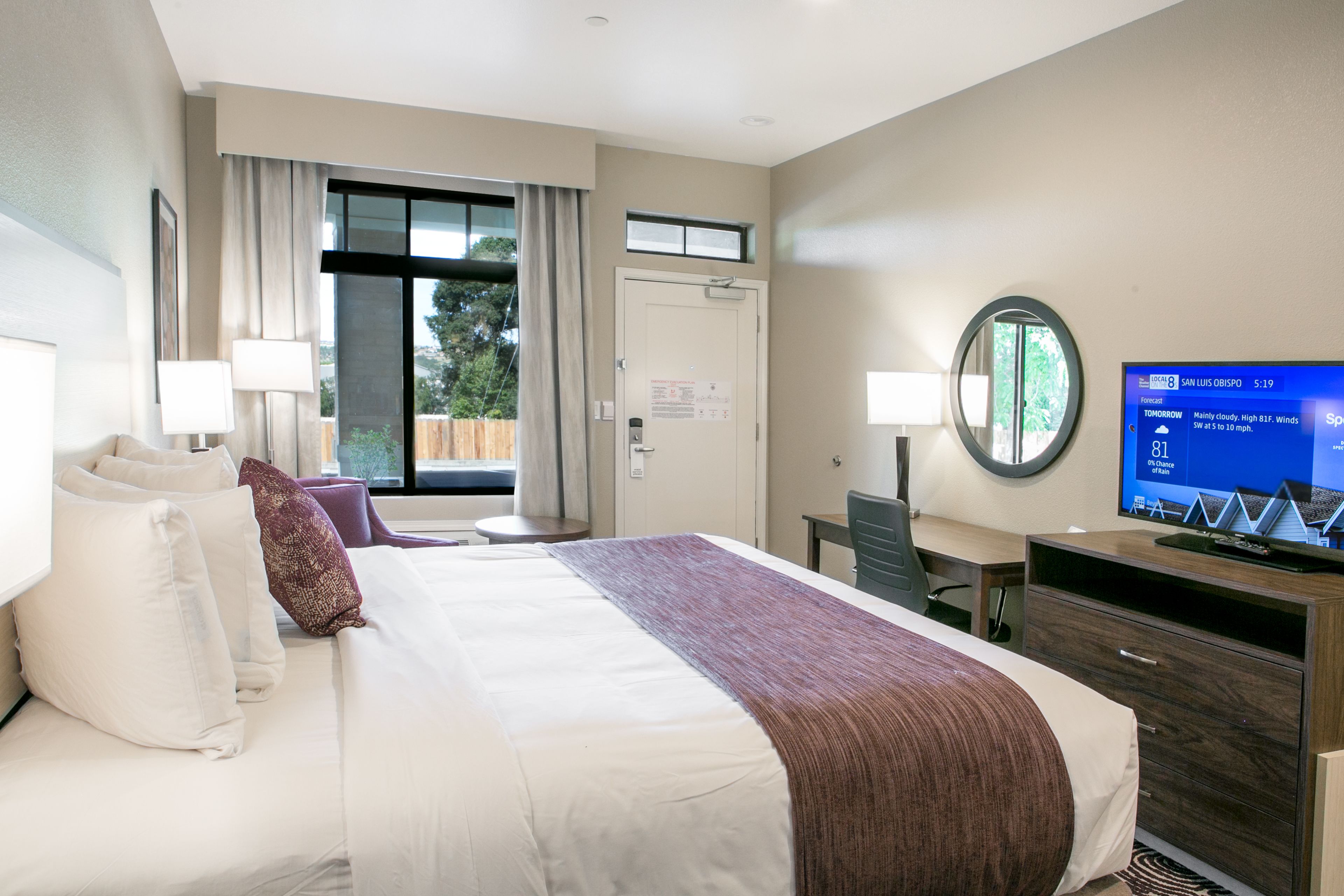 Camera d'albergo con un letto grande, due comodini, una TV e vista sull'esterno.