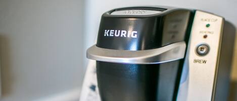 Una cafetera Keurig sobre una encimera, con una cápsula de café y una taza cerca.