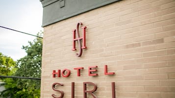 A hotel sign with the name "HOTEL SIRI" on a brick wall.