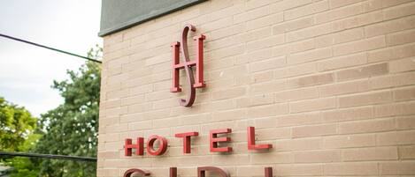 A hotel sign with the name "HOTEL SIRI" on a brick wall.
