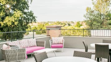 An outdoor patio with wicker furniture, a round table, and a cushioned bench.