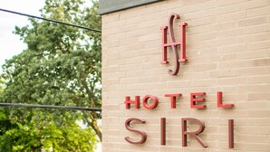 Un letrero de hotel con el nombre "HOTEL SIRI" sobre un muro de ladrillo.