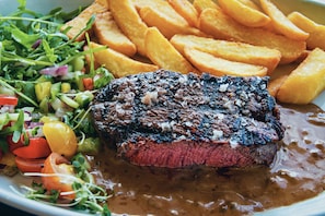 A plate with a steak, fries, and a salad.