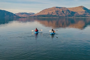 Two kayaks on calm water with mountains in the background.