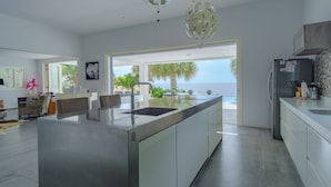 Une cuisine moderne dotée d’un grand îlot central, d’un coin repas offrant une vue agréable et d’un salon spacieux.