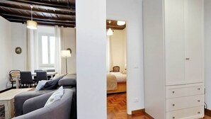 Um quarto com sofá, mesa de jantar, luminária e guarda-roupa.