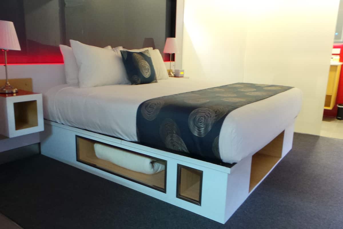 A modern bedroom with a bed, nightstands, and a built-in storage unit.