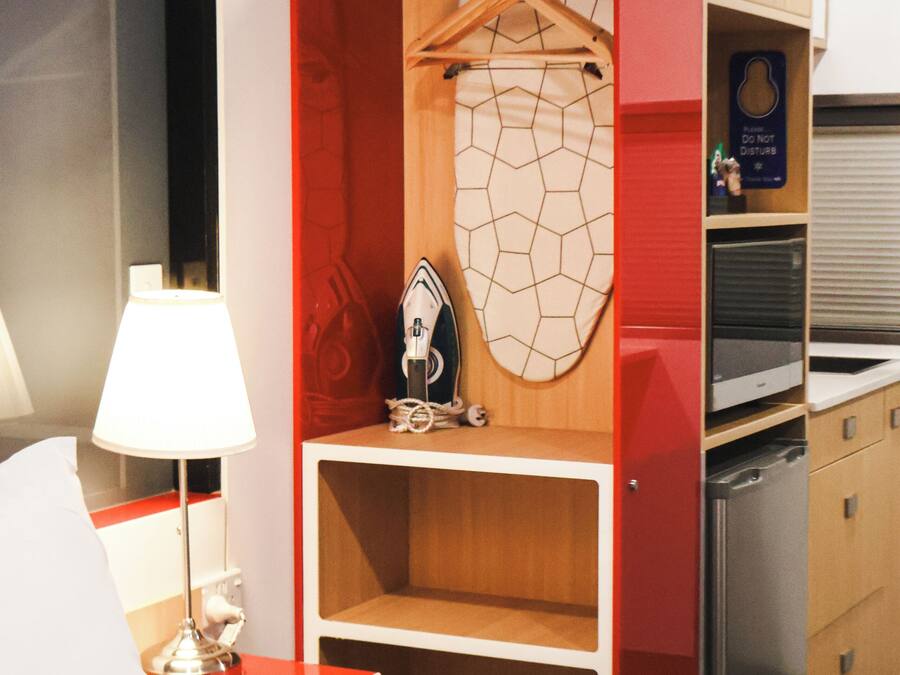 Hotelkamer met een bed, een bureau met lamp, een kledingkast met spiegel en een klein plankje met decoratie.