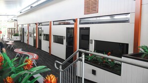 Un pasillo de hotel con habitaciones individuales, una escalera y una barandilla.