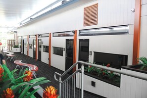 A hotel corridor with individual rooms, a staircase, and a railing. - Stay Motel (Gympie)