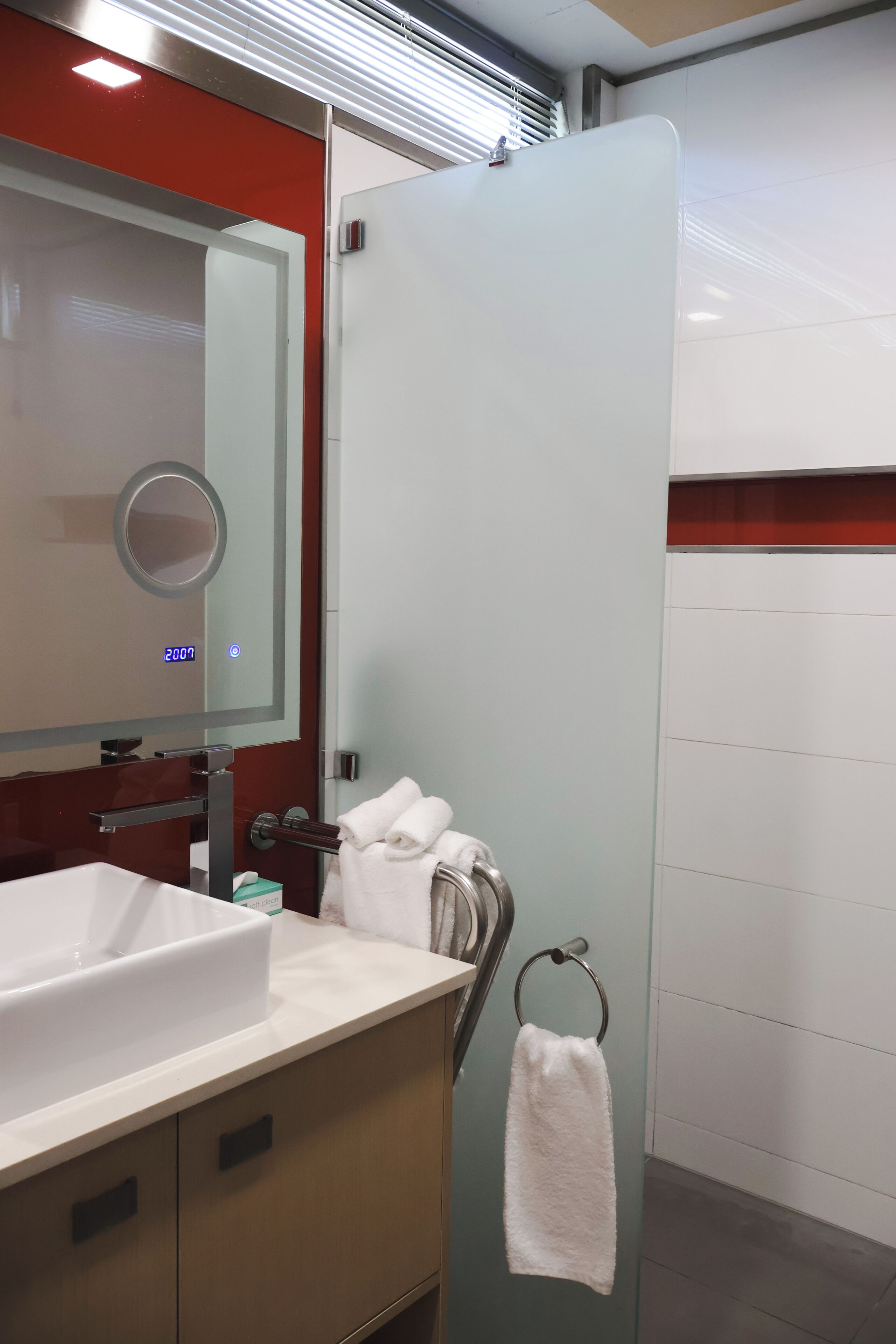 A modern bathroom with a white sink, a mirror, and a glass shower enclosure.