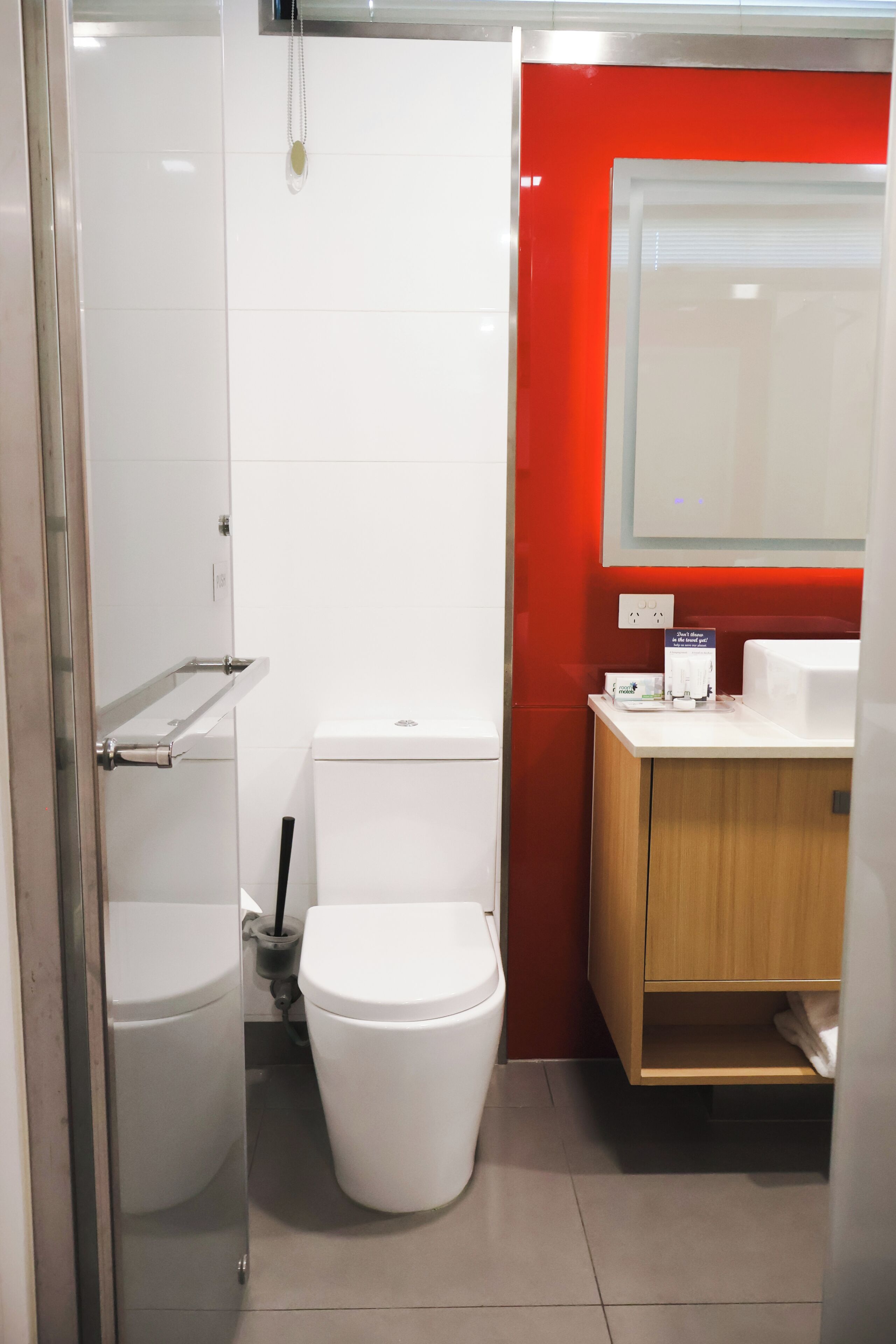 A modern bathroom with a white toilet, a bidet, and a wooden vanity with a mirror.