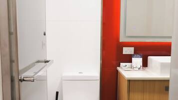 A modern bathroom with a white toilet, a bidet, and a wooden vanity with a mirror.