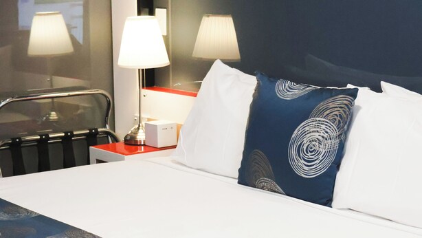 Una habitación de hotel con cama, dos lámparas de noche, una mesita de noche y una ventana.