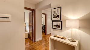 A hallway with wooden flooring, a white console table with a lamp, and two framed artworks on the wall. - Piazza Venezia Apartment 2Bd 2Bt AC WiFi (Roma)