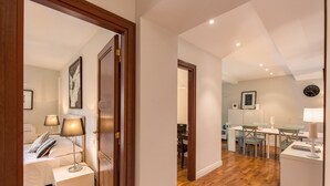 A modern bedroom with a bed, bedside tables, and a nightstand. There is a dining area with a table and chairs. - Piazza Venezia Apartment 2Bd 2Bt AC WiFi (Roma)