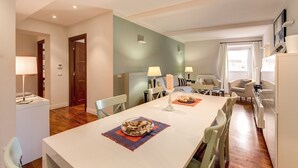 A modern dining area with a long table, chairs, and a central island with a bowl of snacks. - Piazza Venezia Apartment 2Bd 2Bt AC WiFi (Roma)