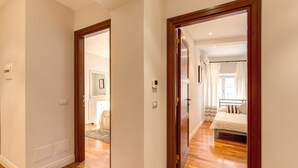 A hallway with wooden flooring and white walls, leading to a bedroom with a bed and curtains. - Piazza Venezia Apartment 2Bd 2Bt AC WiFi (Roma)