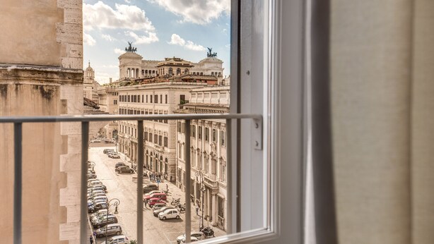 A view from a window overlooking a street with parked cars and historic buildings. - Piazza Venezia Apartment 2Bd 2Bt AC WiFi (Roma)