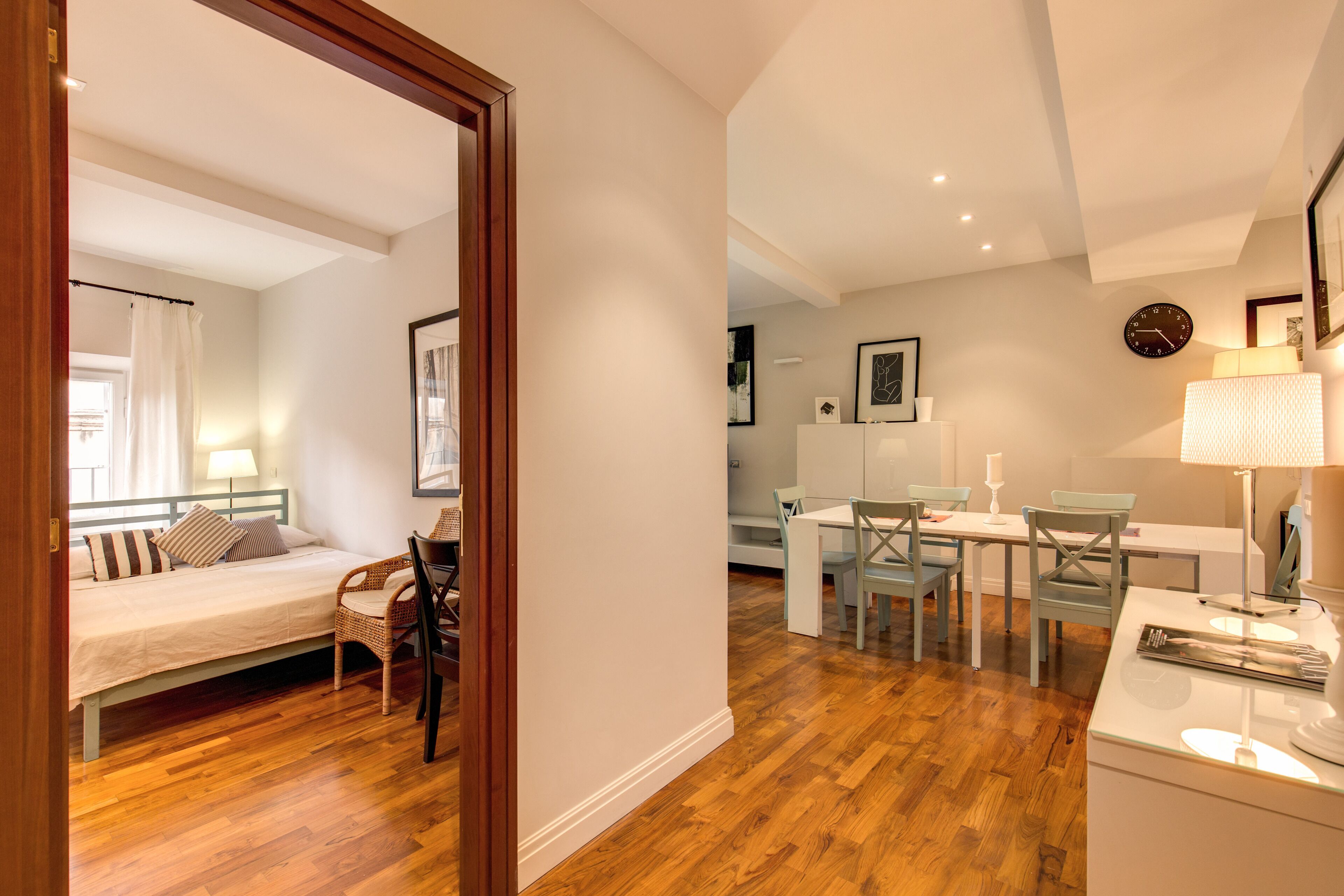 A bedroom with a bed, a chair, and a desk with a lamp.