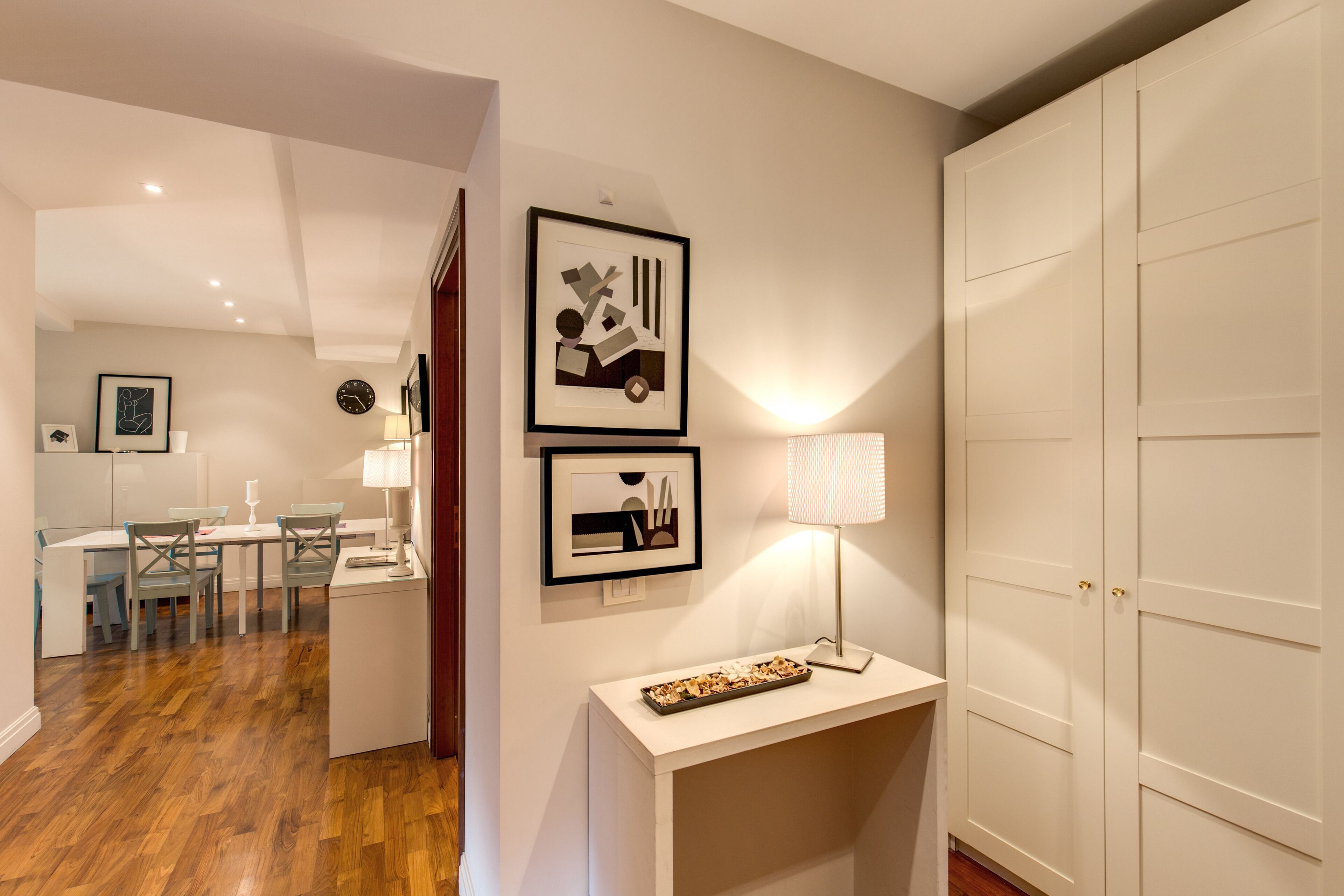 A modern interior with a dining area, white walls, and a wooden floor.