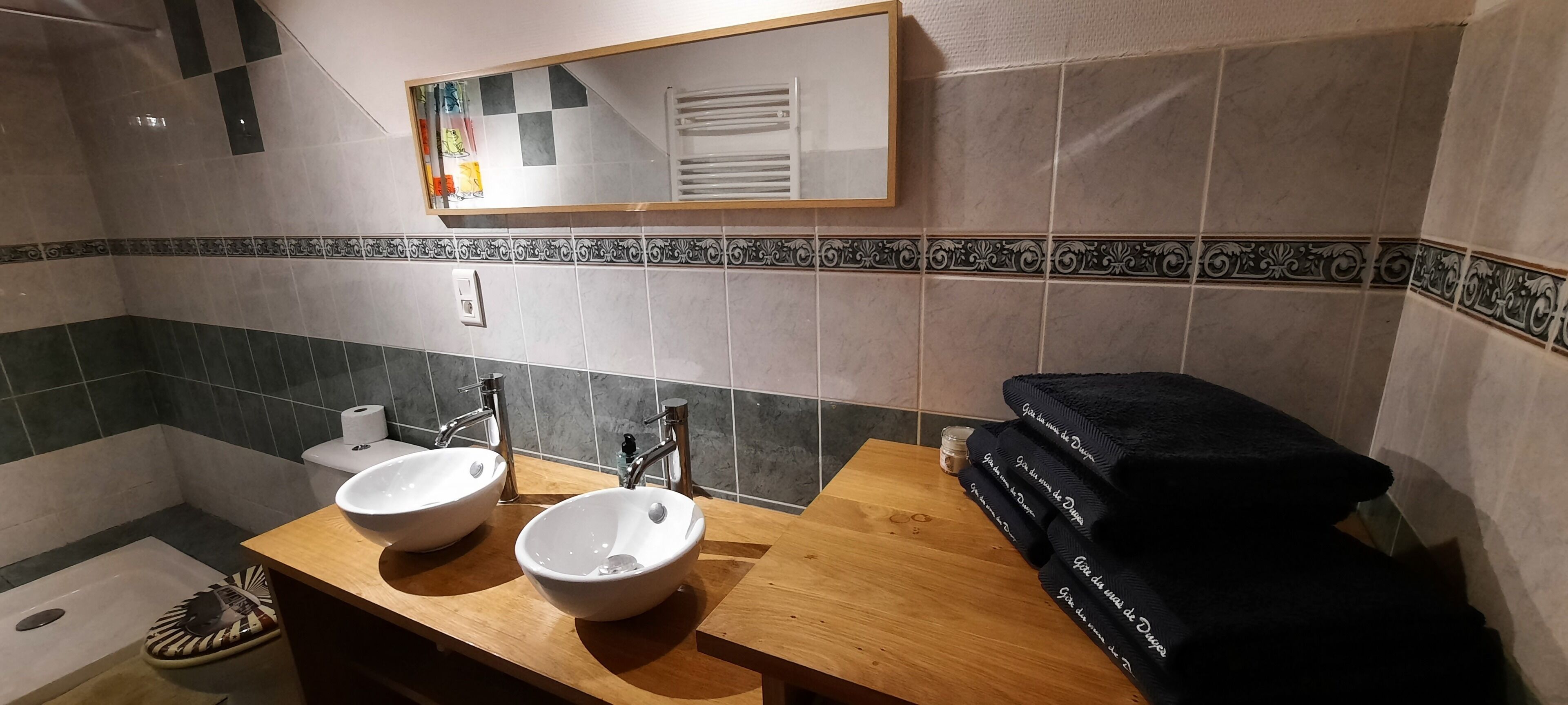 A bathroom with two sinks, a mirror, and a towel rack.