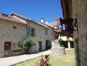 A stone building with a courtyard, a rustic wooden bench, and a metal sculpture. - Authentic cottage, farmhouse, private pool, Caylus / St Antonin Noble Val / 3 stars (caylus)
