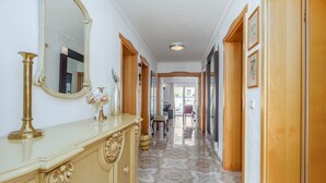 Ein Flur mit einem cremefarbenen Schrank, einem großen Spiegel und einem gemusterten Boden.