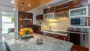 Eine moderne Küche mit Granitarbeitsplatten, Holzschränken, einer eingebauten Mikrowelle und einem Edelstahlbackofen.