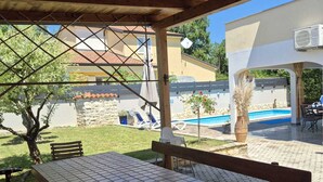 Eine Außenpatio-Terrasse mit Fliesenboden, Holzbanken und einem Tisch.