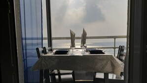 A dining table with chairs and a view of the sea through a window.