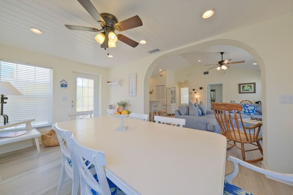 A spacious kitchen with a large island, white cabinetry, and a ceiling fan.