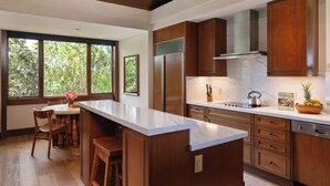 A modern kitchen with wooden cabinets, a marble countertop, and a large window with a view of greenery. - Fairway Villa 120A: Charming w/Shared Pool, AC, 2 Golf Carts & Lanai Ocean Views (Kailua Kona)