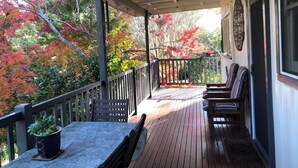 A covered porch with a wooden deck, a table with a potted plant, and a bench. - Bird Hill - A Garden Retreat in the Yarra Valley - Get Up Close to Native Birds (Woori Yallock)