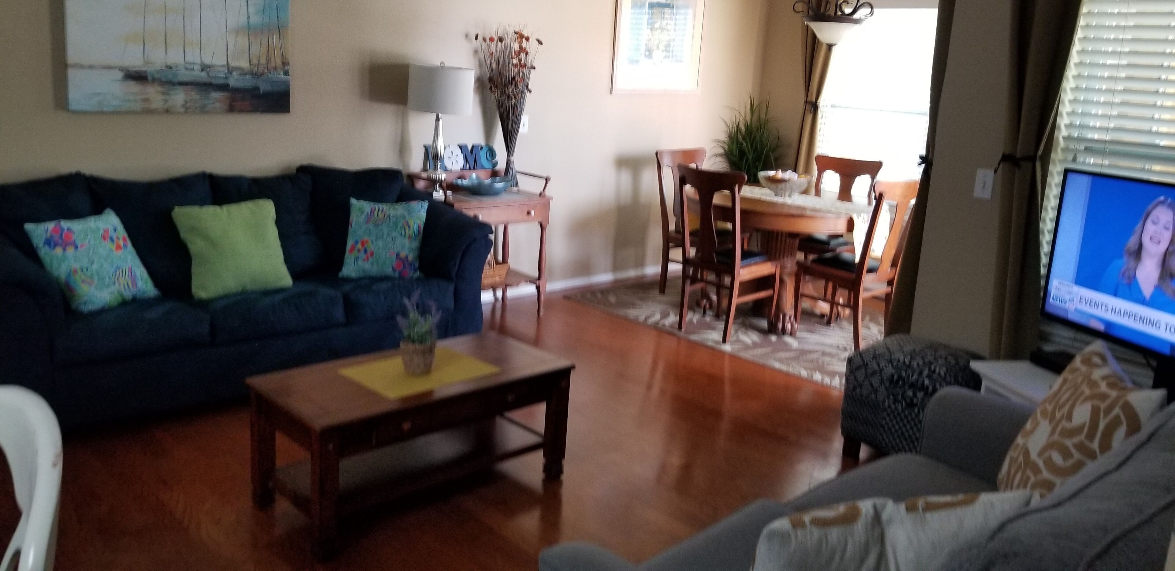 Una sala de estar con un sofá azul oscuro, una mesa de centro de madera y una mesa de comedor con sillas.