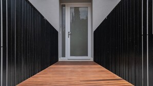 Un bâtiment moderne doté d’une terrasse en bois qui mène à une porte.