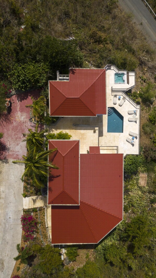 An aerial view of a house with two red-roofed structures, a swimming pool, and a patio area with lounge chairs. - Argonauta: Spectacular Ocean Views, Privacy and Luxury - Minutes from town (st john)